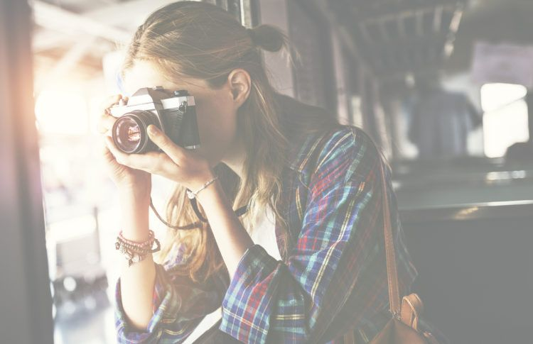 A person wearing a plaid shirt is taking a photograph with a camera.