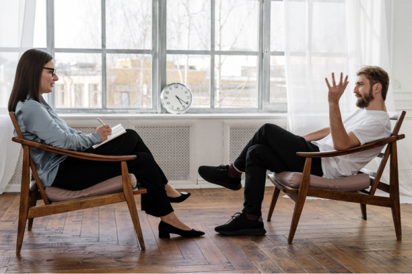 A woman and a man are having a discussion in a bright room.