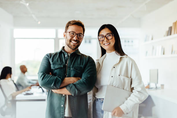 Two professionals smiling in a modern office setting, representing successful businesses in Dubai Free Zones.